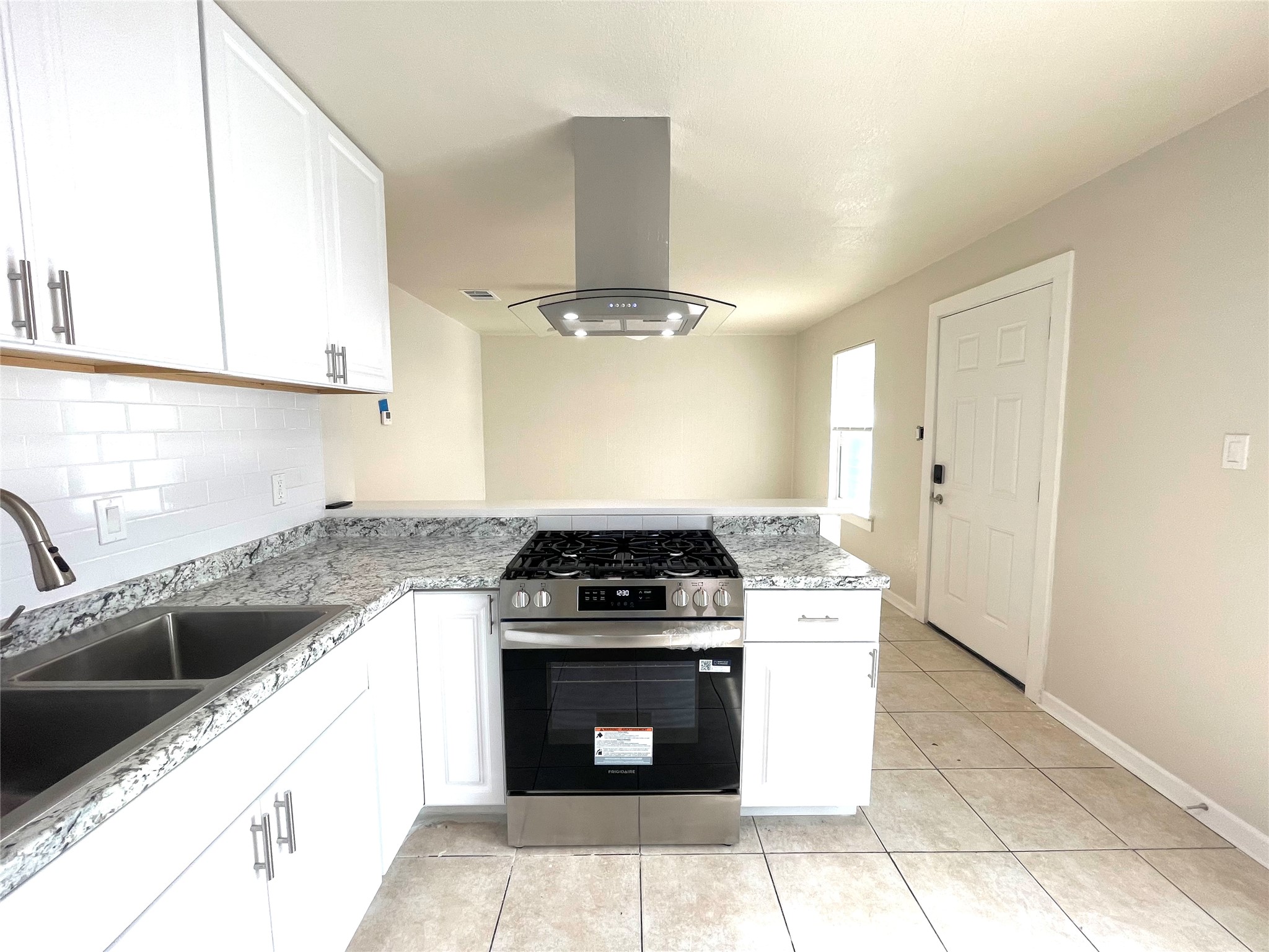 6510 Hickman Avenue, Unit 102 Austin, TX 78723 - Photo 7 of 32 Kitchen featuring stainless steel gas range oven, island range hood, white cabinetry, and light tile patterned floors