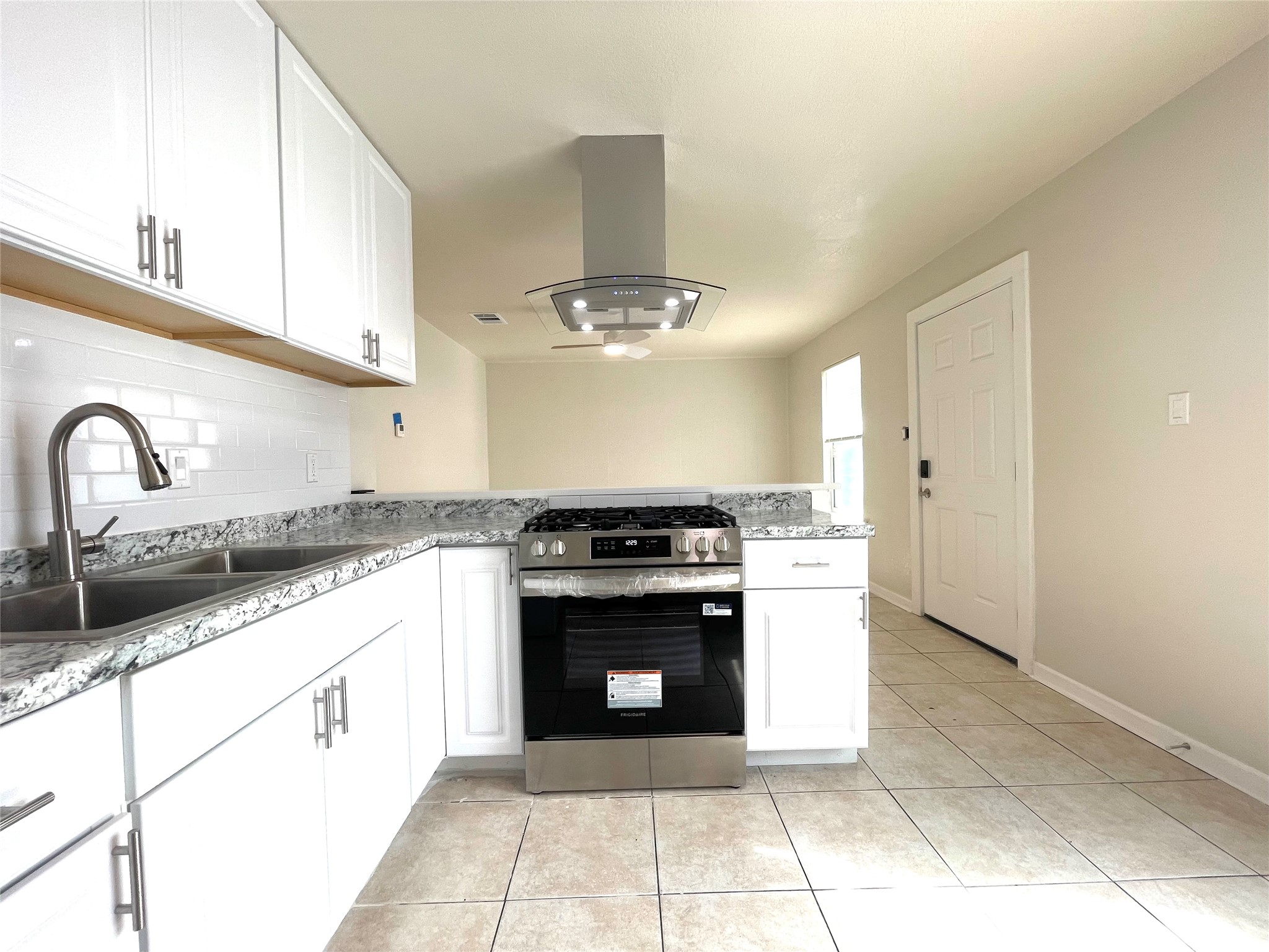 6510 Hickman Avenue, Unit 102 Austin, TX 78723 - Photo 10 of 32 Kitchen featuring a peninsula, stainless steel gas range, white cabinetry, and island range hood