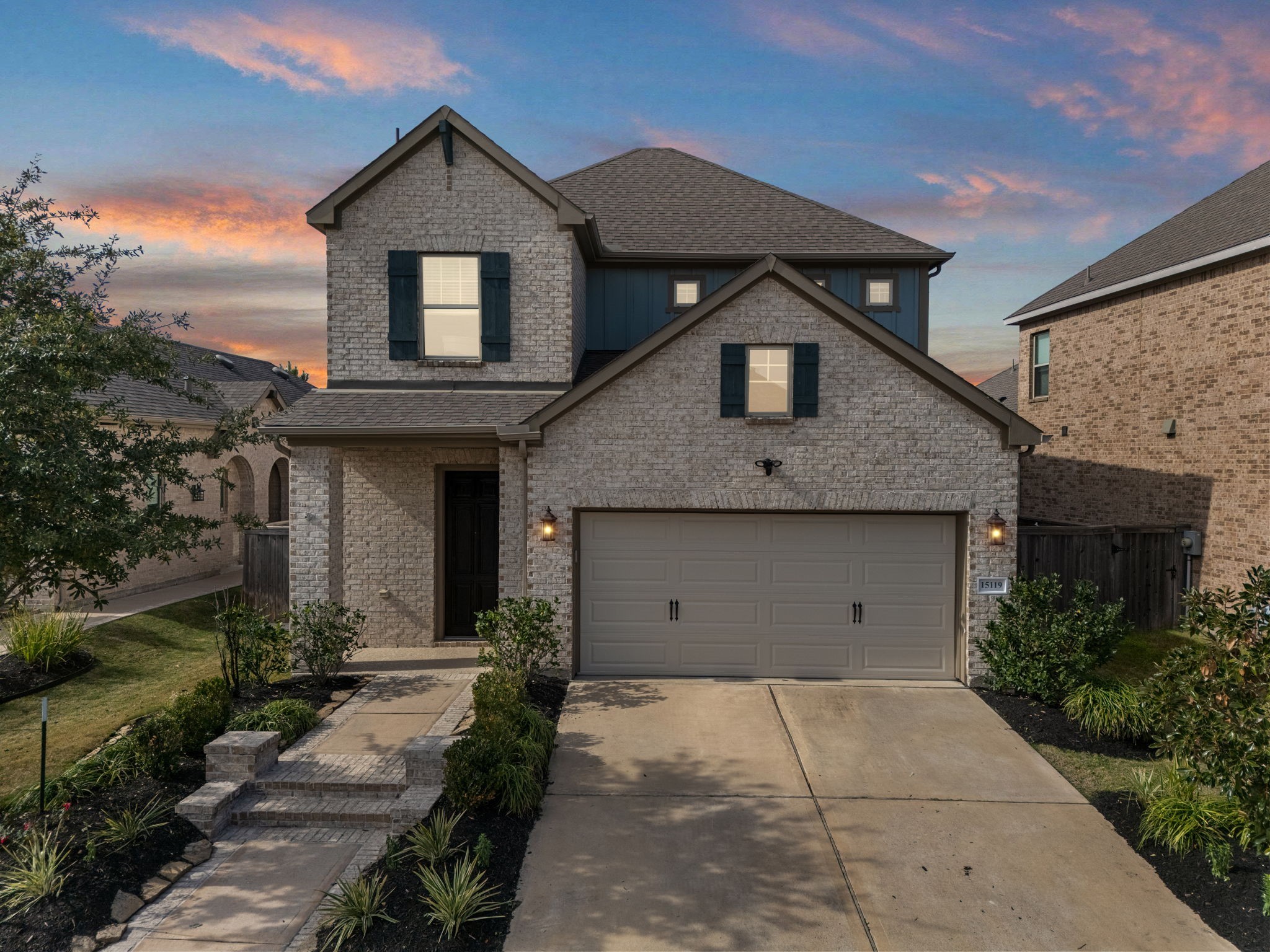This beautiful two-story home greets you with an inviting blend of light-colored brick and warm wood siding, creating a modern yet classic feel that stands out in the neighborhood.