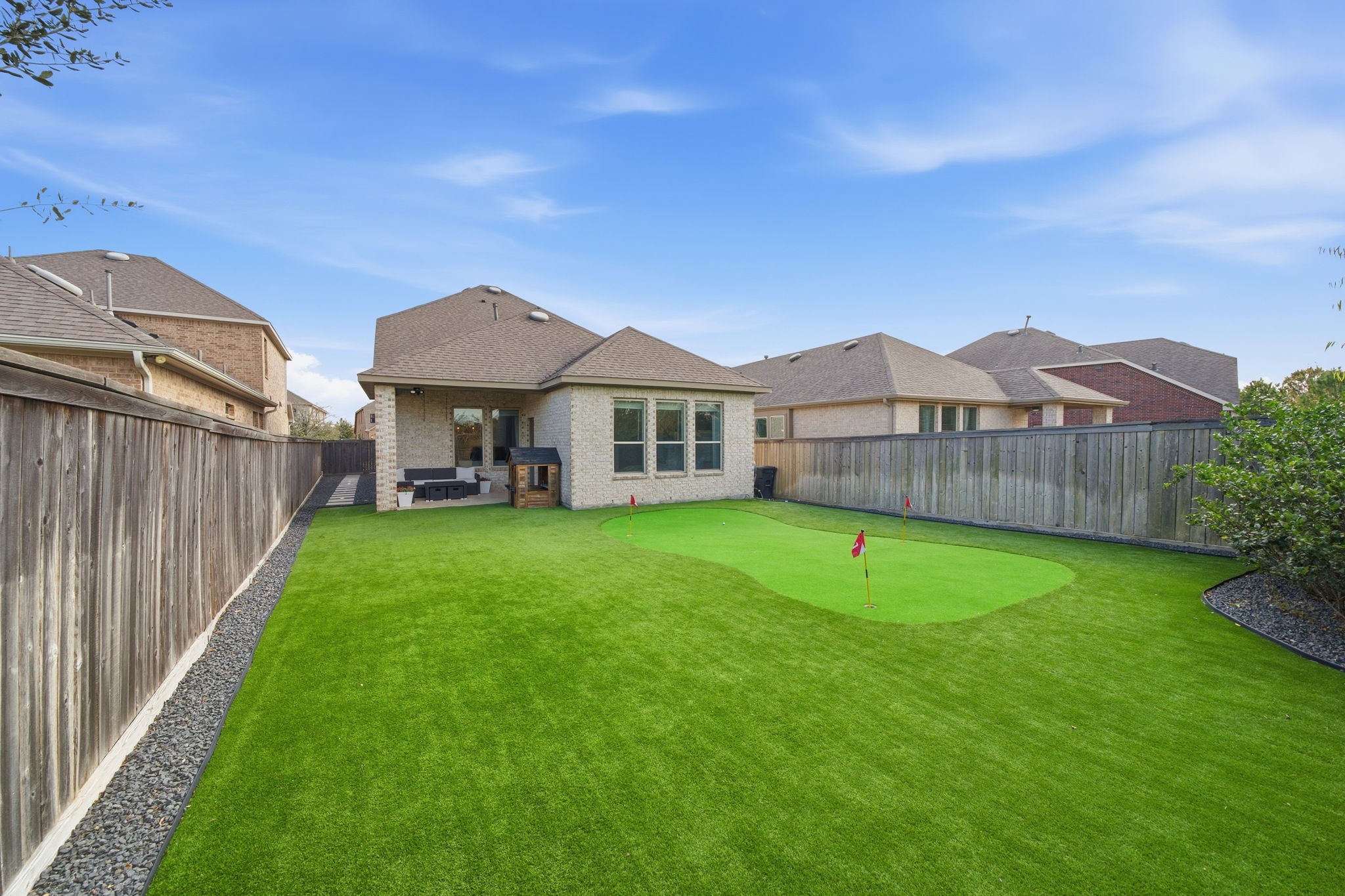 15119 Barbado Ridge Trail Cypress, TX 77433 - Photo 30 of 37 Step outside to discover a backyard designed for ultimate entertainment and low-maintenance living. The highlight of the outdoor space is a professional-grade putting green, surrounded by lush, high-quality artificial turf that stays perfectly green year-round without the hassle of mowing.