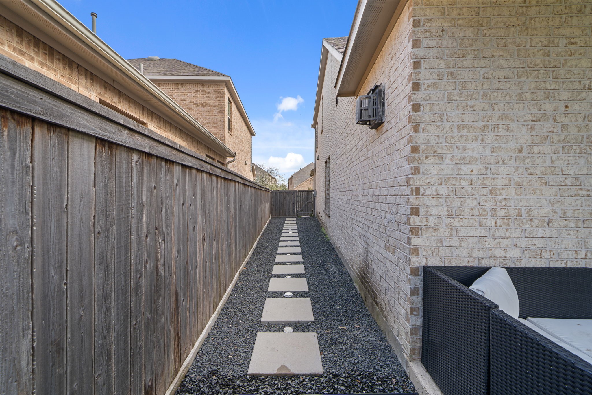 15119 Barbado Ridge Trail Cypress, TX 77433 - Photo 33 of 37 The space is thoughtfully detailed with a modern stone-paved walkway set against dark river rock, leading you through the side yard.