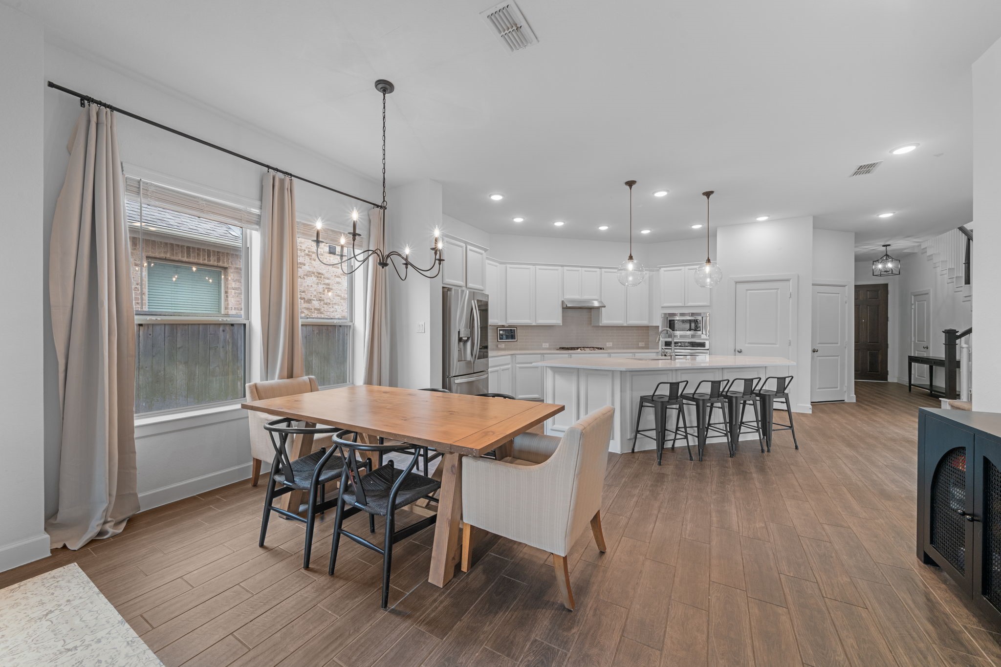 15119 Barbado Ridge Trail Cypress, TX 77433 - Photo 9 of 37 A classic wrought-iron chandelier hangs above the table, providing a sophisticated focal point that balances the room's modern aesthetic with a touch of timeless charm.