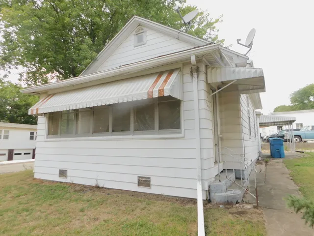 a small white building with a white roof and table and chairs under an umbrella
