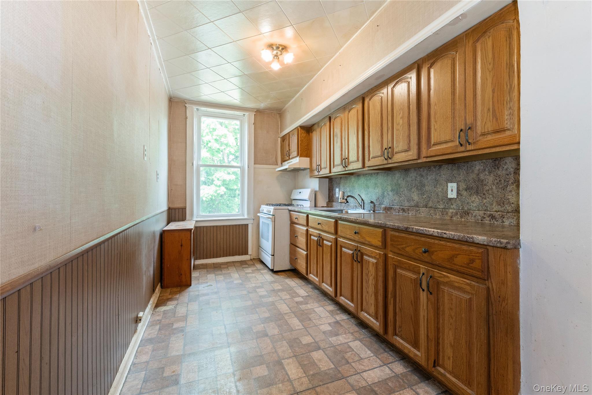 82-72 88th Place Queens, NY 11421 - Photo 13 of 26 a kitchen with granite countertop a sink window and cabinets