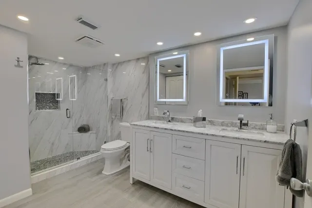 a bathroom with a double vanity sink toilet mirror and shower