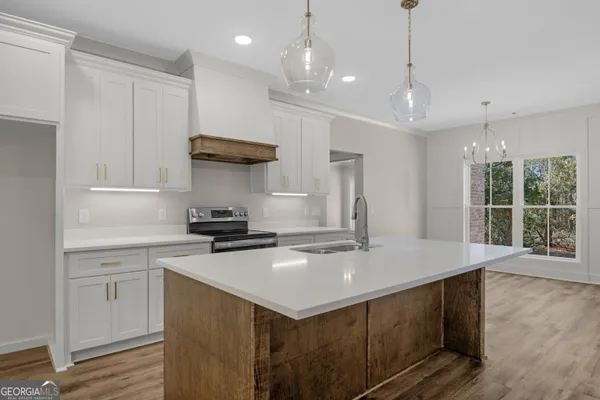 a kitchen that has a sink a stove and a wooden floor