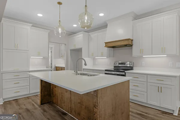 a kitchen with a stove a sink a center island and windows