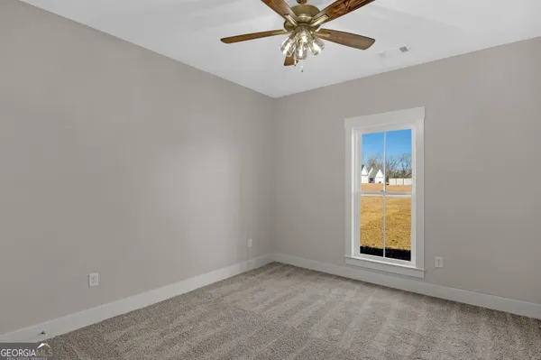 an empty room with windows and chandelier fan