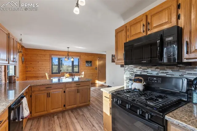 a kitchen with stainless steel appliances a stove a sink dishwasher a microwave oven and a stove with wooden floor