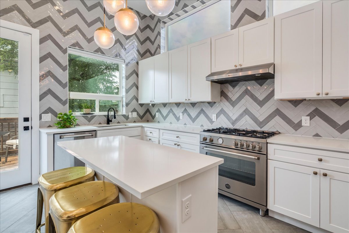 a kitchen with a stove a sink cabinetry and a chandelier