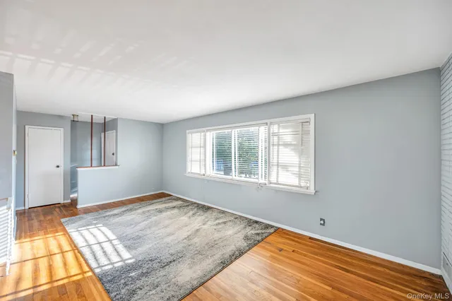 a view of a bedroom with wooden floor and window