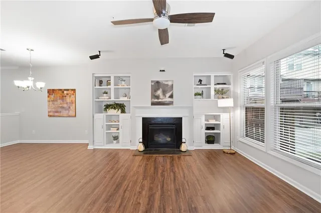 an empty room with windows fireplace and wooden floor