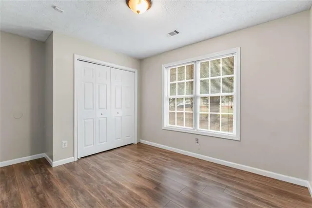 an empty room with wooden floor and windows
