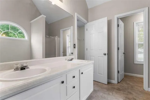a bathroom with a sink double vanity granite tub shower and a mirror