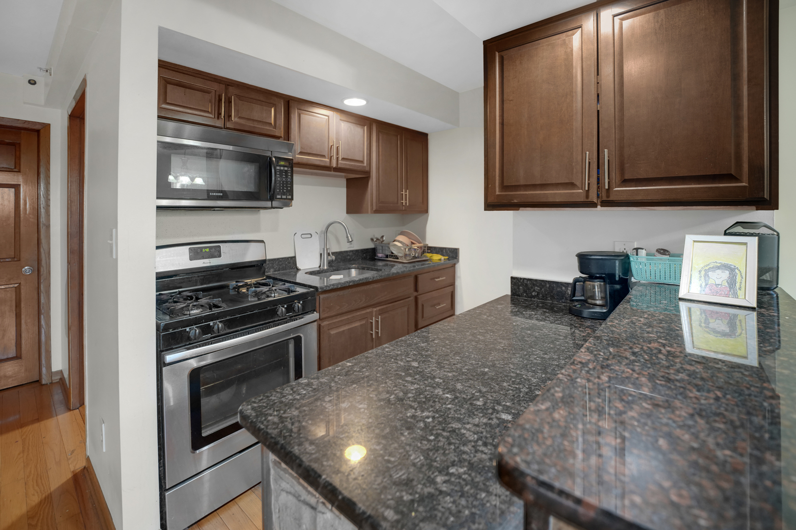 8845 West 75th Street Justice, IL 60458 - Photo 6 of 14 a kitchen with stainless steel appliances granite countertop a stove microwave and sink