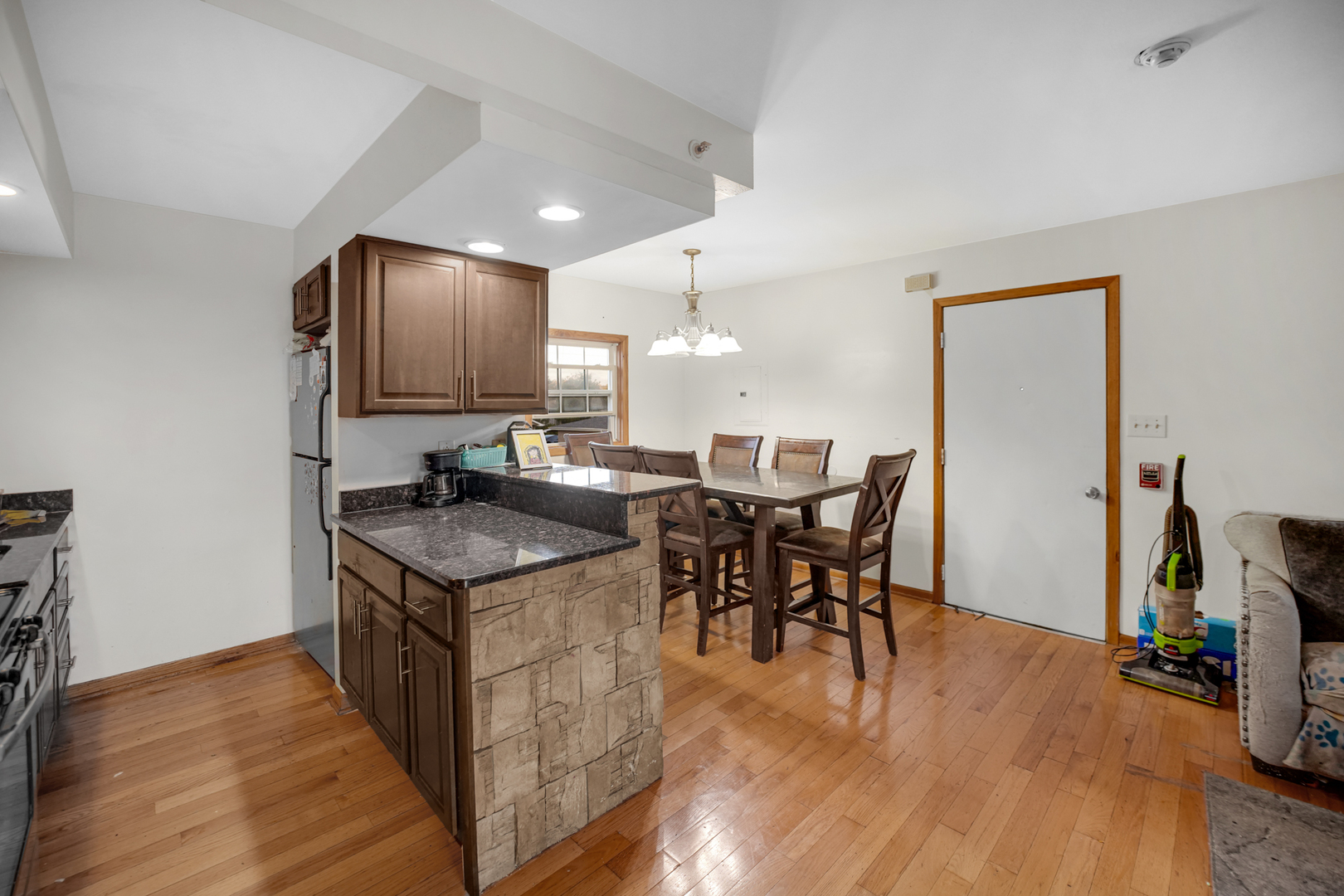 8845 West 75th Street Justice, IL 60458 - Photo 7 of 14 a kitchen with stainless steel appliances granite countertop a stove top oven a sink a dining table and chairs with wooden floor