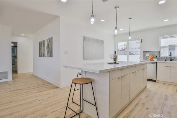 a kitchen with stainless steel appliances kitchen island granite countertop a stove a sink a microwave a dining table and chairs with wooden floor