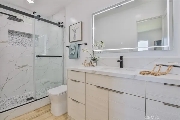 a bathroom with a granite countertop sink a toilet and shower
