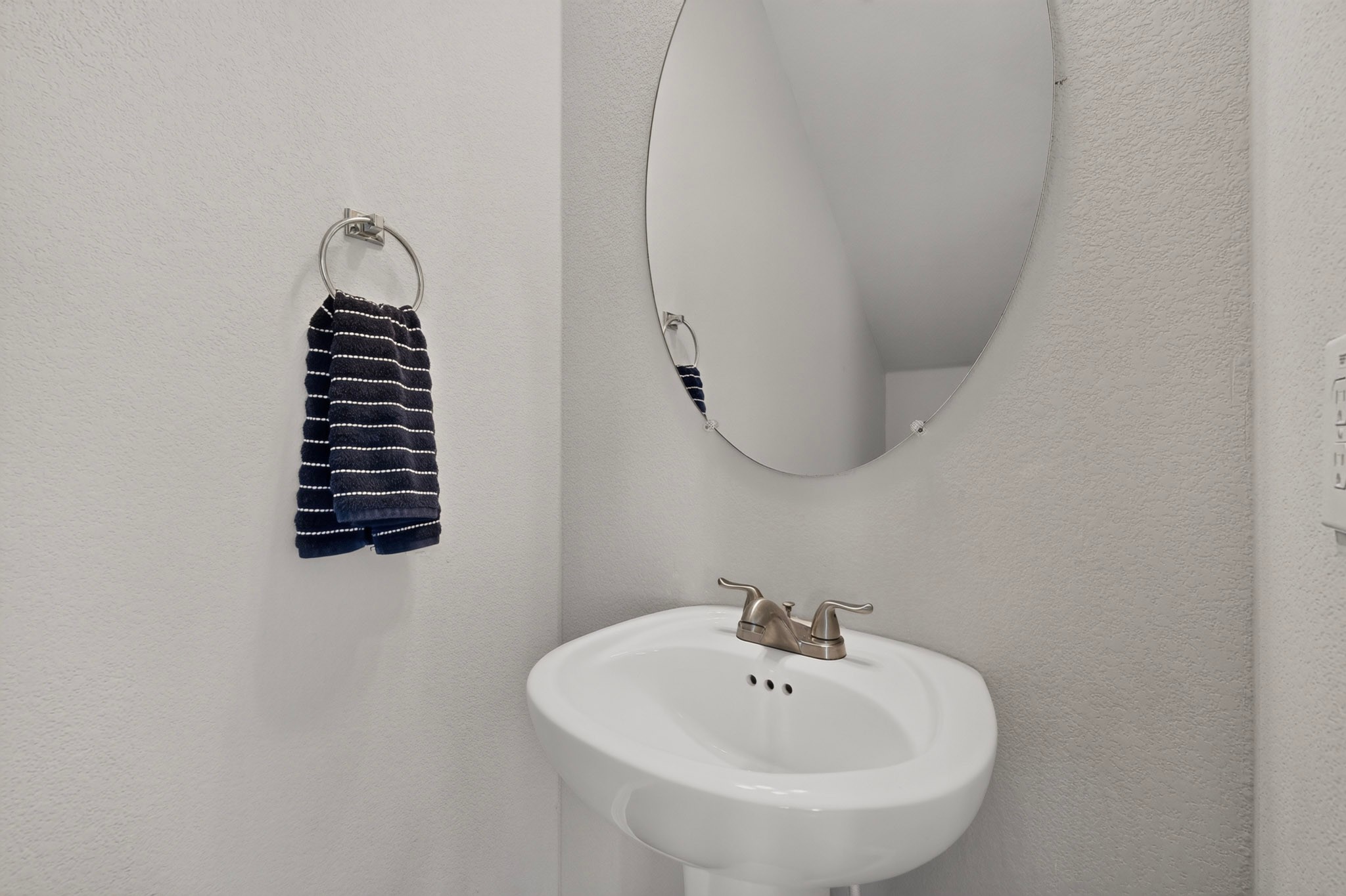 132 Wapiti Road Buda, TX 78610 - Photo 8 of 31 A well-appointed half-bath with a sleek pedestal sink and a contemporary oval mirror.