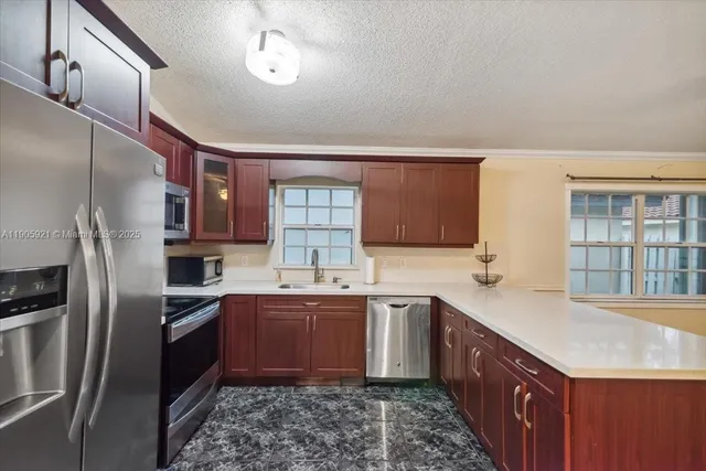 a kitchen with granite countertop a sink stainless steel appliances and cabinets