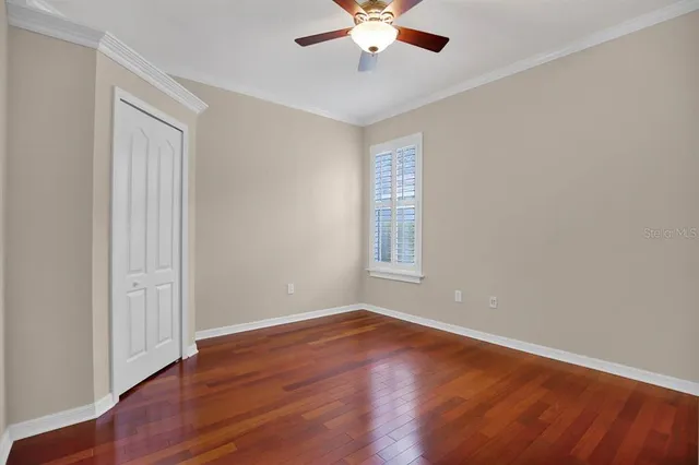 an empty room with wooden floor chandelier fan and windows