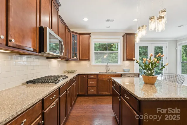 a kitchen with stainless steel appliances granite countertop a sink stove and cabinets