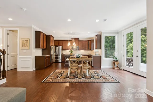 a living room with stainless steel appliances furniture wooden floor and a kitchen view