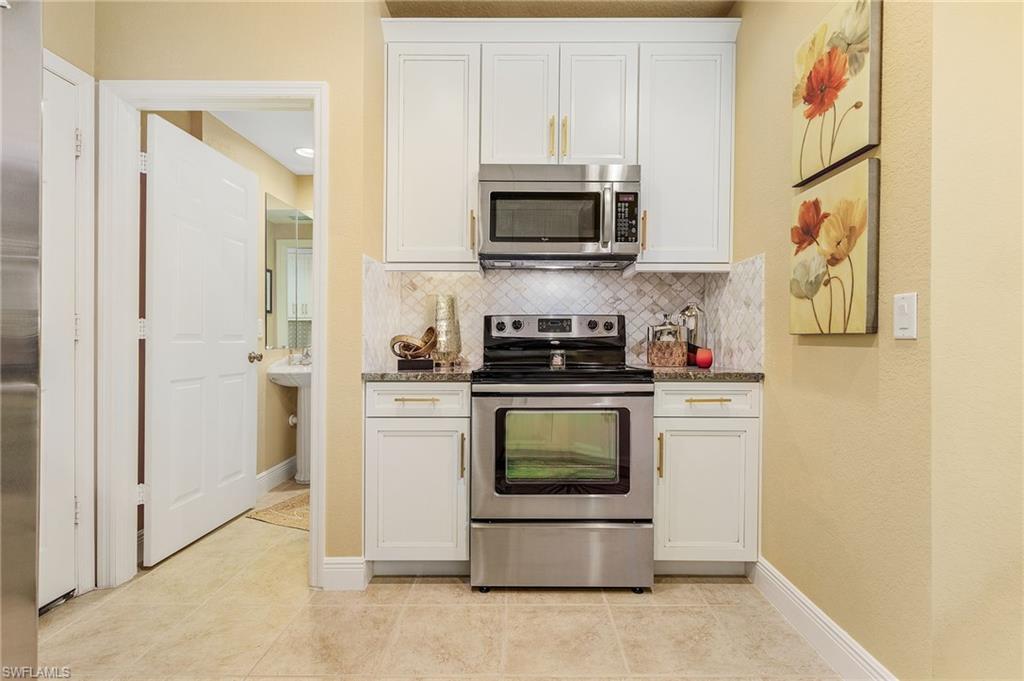 9803 Bodego Way, Unit 104 Fort Myers, FL 33908 - Photo 10 of 31 a kitchen with stainless steel appliances a stove a microwave a refrigerator and cabinets