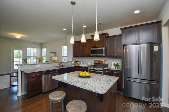 a kitchen with refrigerator a sink and chairs
