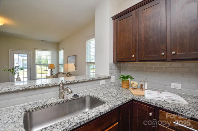 a kitchen with granite countertop a sink a stove and cabinets