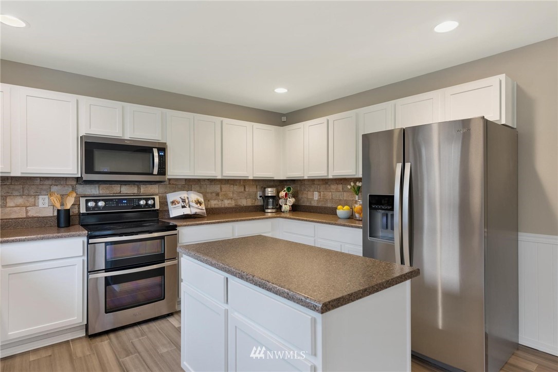 15429 38th Drive Southeast Bothell, WA 98012 - Photo 7 of 26 a kitchen with granite countertop a refrigerator and a stove top oven