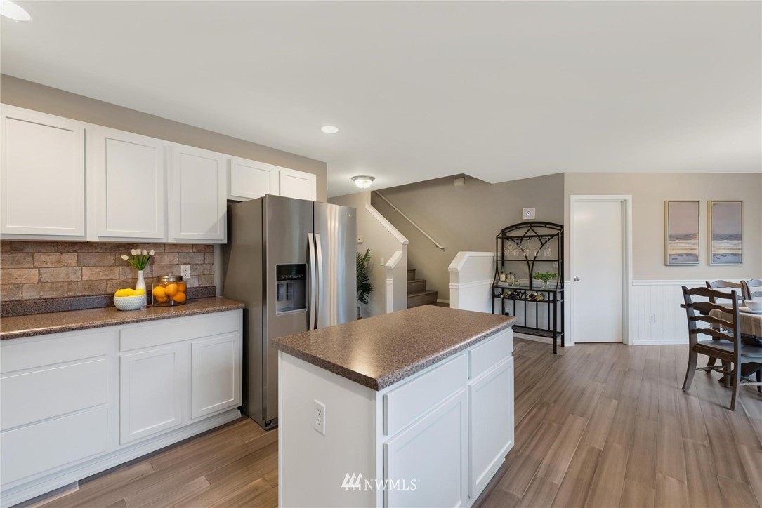 15429 38th Drive Southeast Bothell, WA 98012 - Photo 9 of 26 a kitchen with granite countertop a refrigerator a stove a sink a dining table and chairs with wooden floor