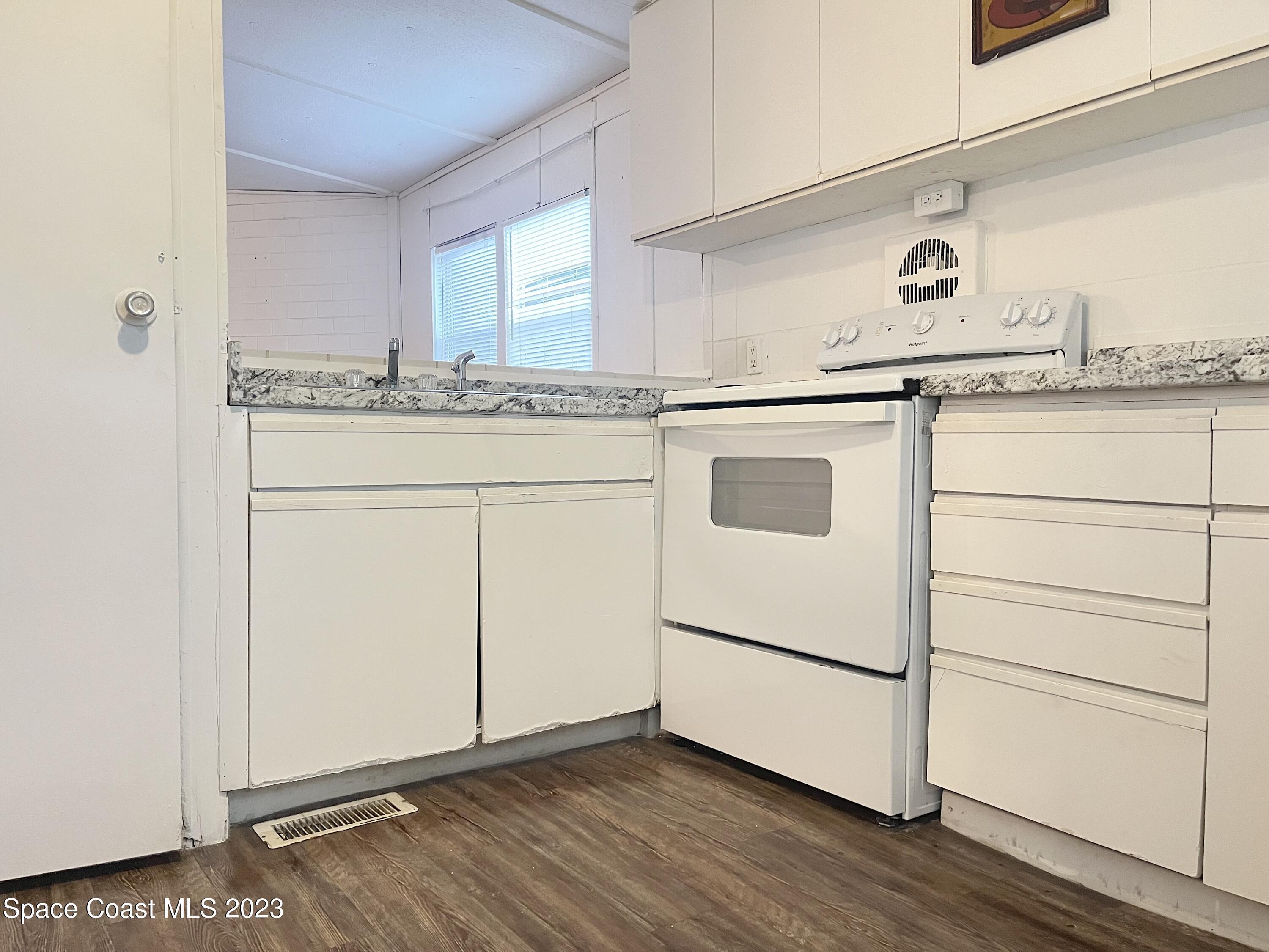 421 Cross Road Cocoa, FL 32926 - Photo 4 of 18 a kitchen with granite countertop cabinets appliances and a wooden floor
