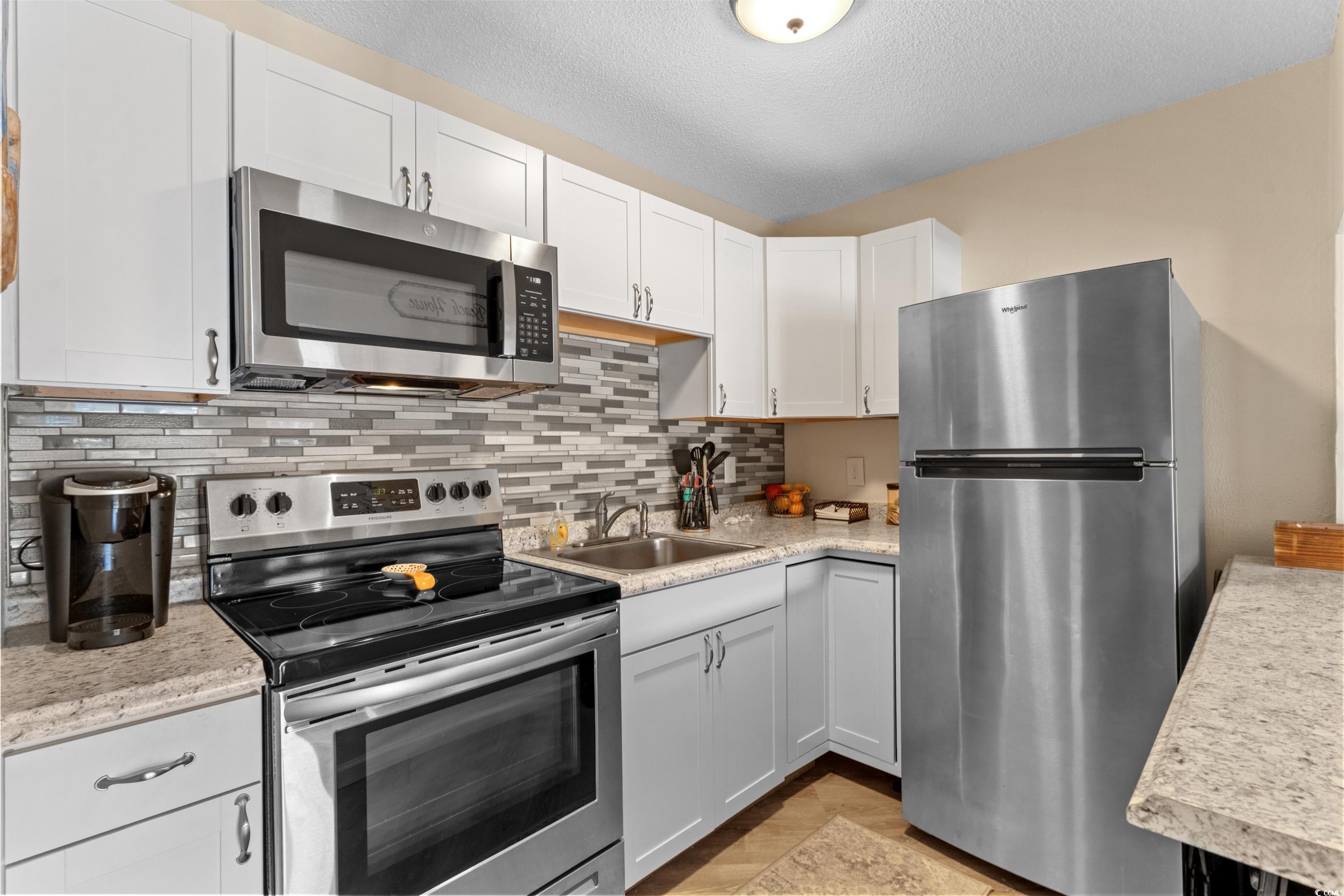 625 North Waccamaw Drive, Unit 107 Murrells Inlet, SC 29576 - Photo 10 of 37 Kitchen with appliances with stainless steel finishes, a sink, light countertops, decorative backsplash, and white cabinets