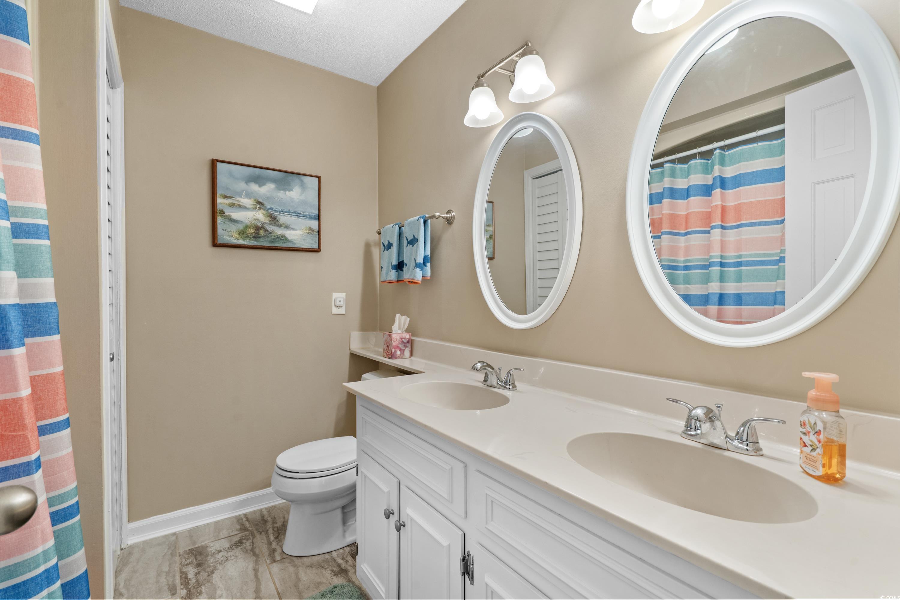 625 North Waccamaw Drive, Unit 107 Murrells Inlet, SC 29576 - Photo 19 of 37 Bathroom featuring toilet, double vanity, baseboards, marble look tile flooring, and a shower with curtain