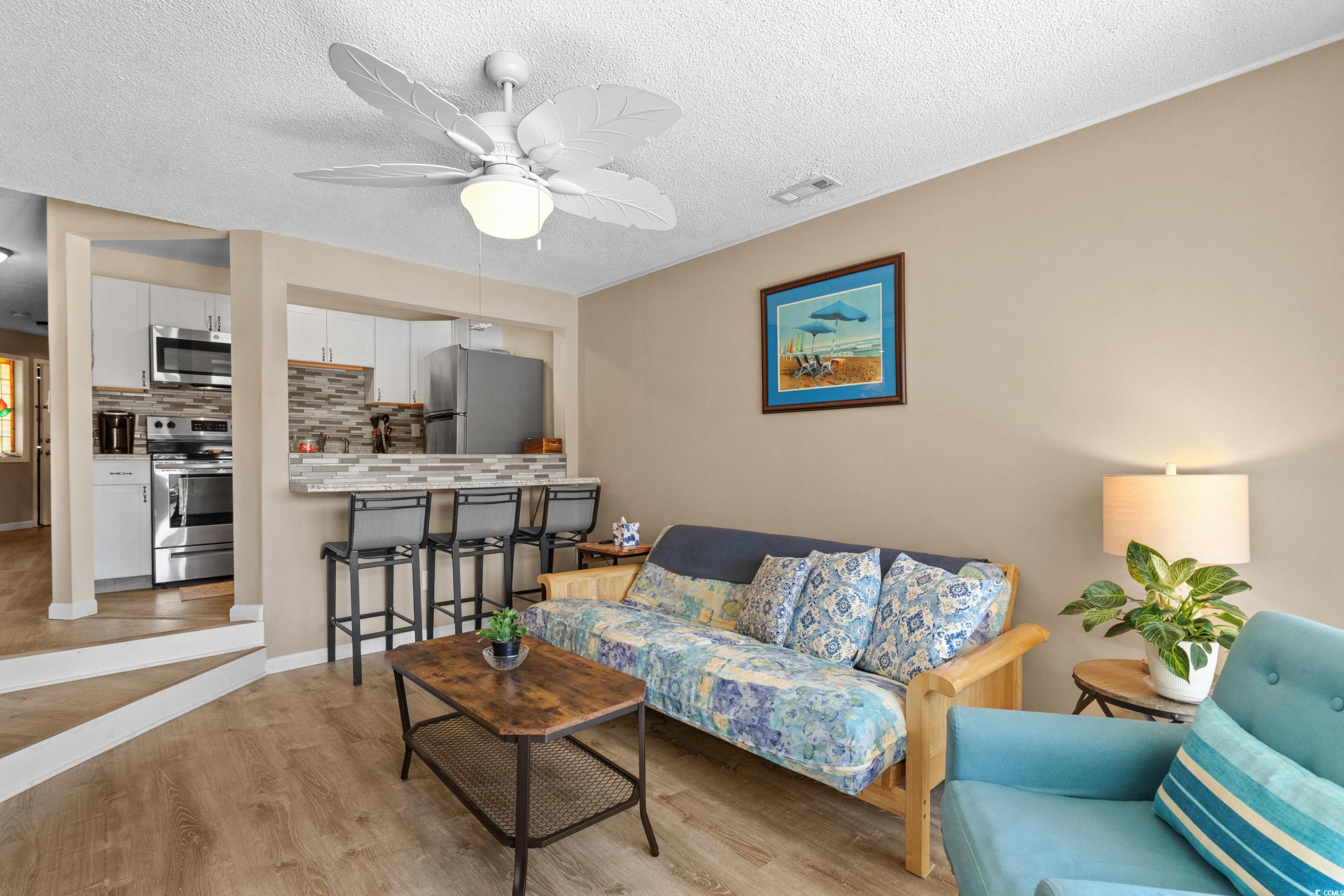 625 North Waccamaw Drive, Unit 107 Murrells Inlet, SC 29576 - Photo 8 of 37 Living area featuring light wood finished floors, a ceiling fan, and a textured ceiling