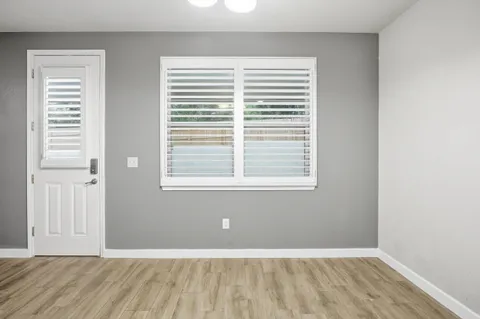 a view of an empty room with wooden floor and a window