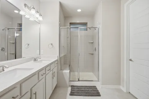 a spacious bathroom with a double vanity sink a large mirror a shower and vanity