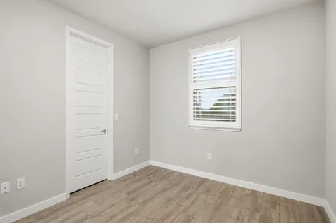 an empty room with wooden floor and window