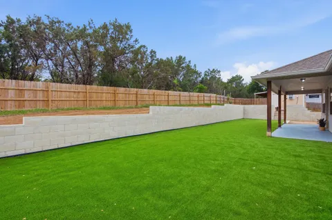 a view of a backyard with large trees and wooden fence