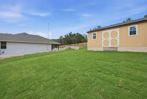 a backyard of a house with lawn chairs and a large tree