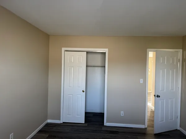 a view of an empty room with wooden floor and closet