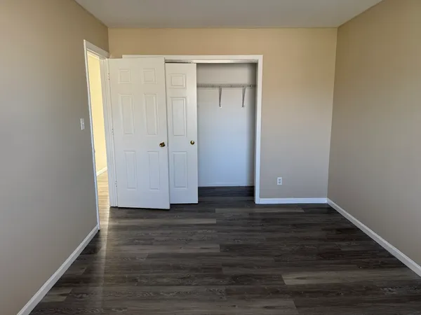 a view of an empty room with wooden floor and closet