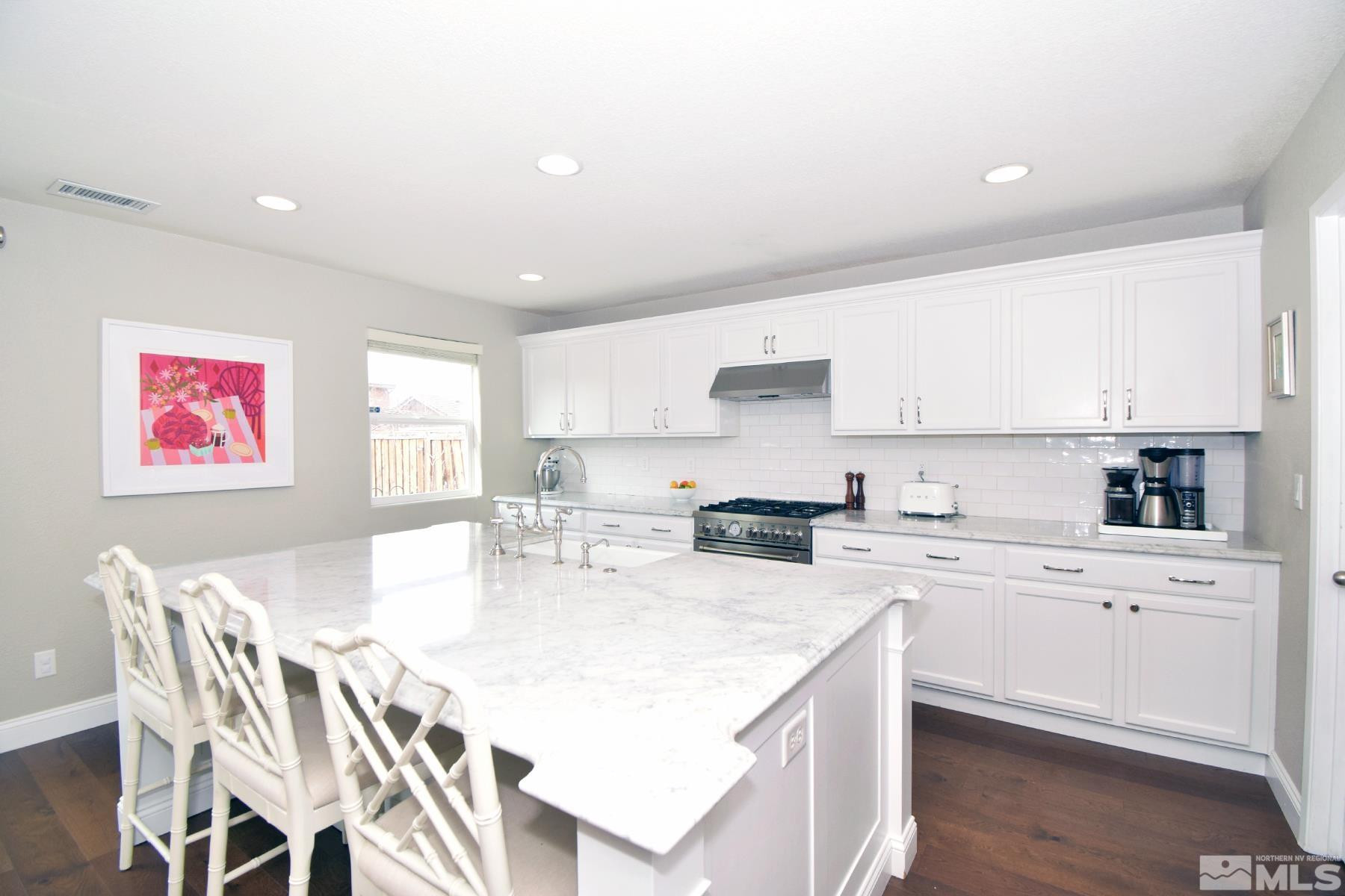 11635 Verazae Drive Reno, NV 89521 - Photo 4 of 27 a kitchen with stainless steel appliances kitchen island granite countertop a stove a sink a dining table and chairs