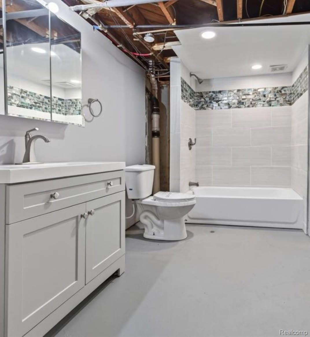 316 Sheffield Avenue Flint, MI 48503 - Photo 4 of 32 Vanity with white countertop, chrome faucet, medicine cabinet with mirror, white toilet, and white bathtub with tiled surround