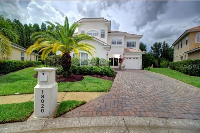 a front view of a house with garden and trees