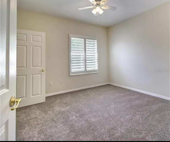 an empty room with windows and fan