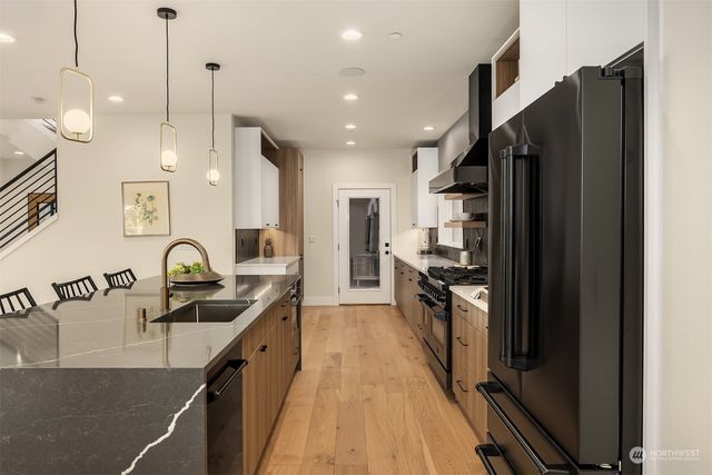a kitchen with granite countertop a refrigerator a sink a stove and cabinets