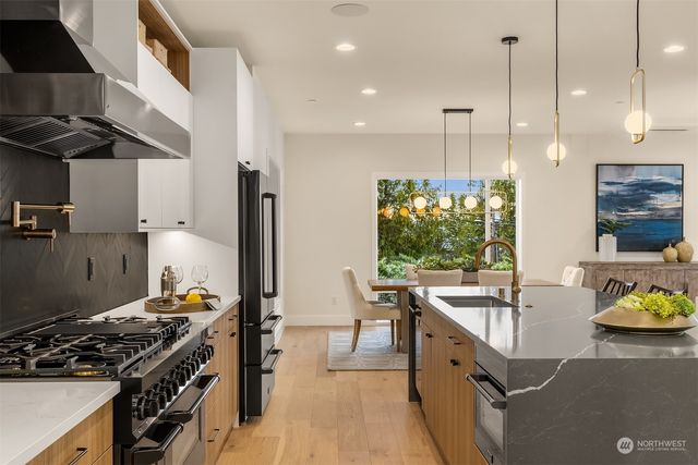 a kitchen with stainless steel appliances granite countertop a stove a sink a refrigerator and a wooden cabinets