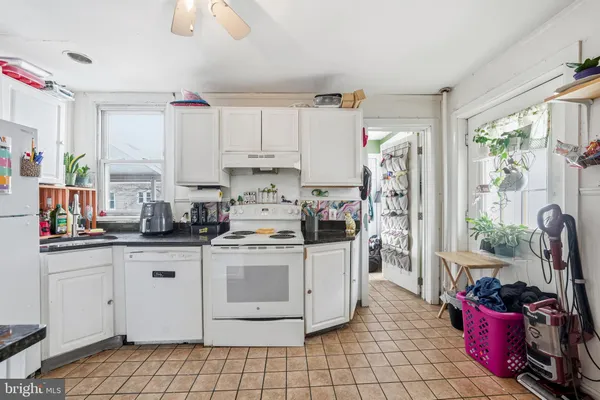 a kitchen with kitchen island a stove a sink dishwasher and white cabinets with wooden floor